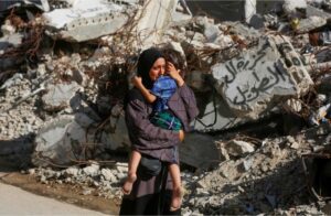 A Palestinian woman cries as she hugs her child following a deadly Israeli attack on the Bureij refugee camp in Gaza on Thursday [Ashraf Amra/Anadolu]