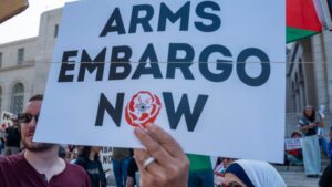 A protester holding up a sign calling for an arms embargo on Israel. (Photo: Social media)