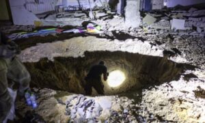 Members of Israel’s home front inspect a crater at a school in Gedera. Photograph: Menahem Kahana/AFP/Getty Images