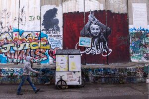 A Palestinian man passes the graffiti showing Marwan Barghouti, a Palestinian imprisoned politician on December 24, 2023 in Bethlehem, West Bank