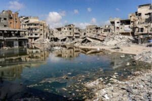 Sewage water from collapsed underground pipes covers an area by destroyed buildings in Khan Yunis in the southern Gaza Strip on July 8, 2024.