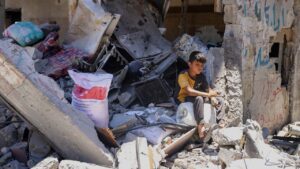 A Palestinian boy sits atop the rubble of a destroyed building in the Jabalia refugee camp on 30 May 2024