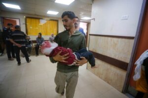 A Palestinian man carries a child with a head injury as injured Palestinians are brought to al-Aqsa Martyrs Hospital for medical treatment after the Israeli attacks on Nuseirat Refugee Camp in Deir al-Balah, Gaza on November 01, 2024