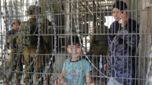 Palestinian child stands at an Israeli checkpoint in Hebron in the occupied West Bank