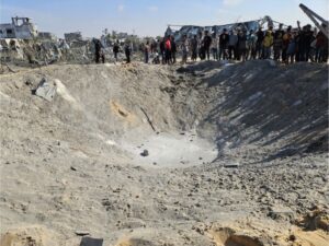 Palestinians gather around a crater, left by an Israeli attack on the al-Mawasi area, where thousands of Palestinians are living in makeshift tents, in Khan Younis, southern Gaza, on Wednesday, Nov. 13