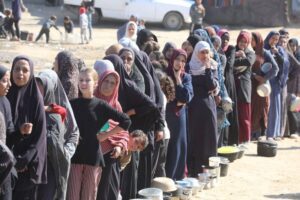 Palestinians, including children, wait to receive food distributed by an aid organisation in, Gaza on November 18, 2024