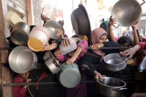 Palestinians, including children, living in the Nuseirat refugee camp wait with empty pots to receive food distributed by an aid organization, in Gaza City, Gaza on November 08, 2024