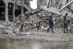 Palestinians walk near a pile of rubble on a rainy day in Jabaliya, Gaza on September 01, 2024.