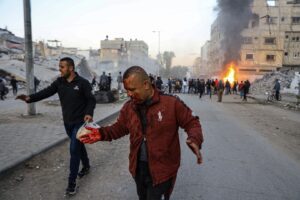 Injured Palestinians run in the aftermath of an Israeli air strike, in Gaza City, Thursday