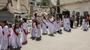 Child deaconesses walk past the rubble of a collapsed building in a procession during the Palm Sunday service outside the Greek Orthodox Church of St Porphyrius in Gaza City on April 28, 2024.