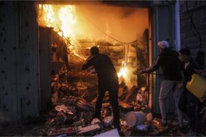 Palestinians try to extinguish the fire in a store after an Israeli attack on the Omar al-Mukhtar market in Gaza City on Monday, Dec. 2