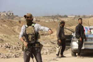 An armed man gestures at a checkpoint at the Netzarim corridor as displaced Palestinians make their way to the northern parts of the Gaza Strip, on January 29, 2025.