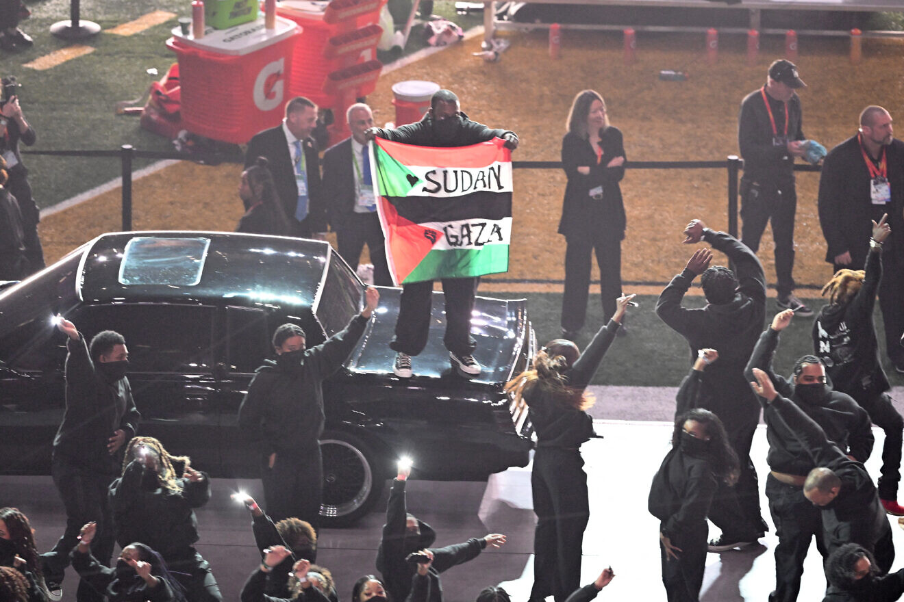 A protestor holds a Palestinian flag with the words "Gaza" and "Sudan" as U.S. rapper Kendrick Lamar performs during Super Bowl LIX Halftime Show, Feb. 9, 2025.