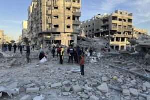 Palestinians inspect a building and wrecked vehicles after Israeli airstrike in Gaza Strip on January 14, 2025