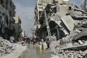 Palestinians collect water next to a building that is in danger of collapsing in Beit Lahia, northern Gaza.