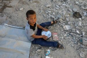 Palestinian child waits as the US-based international volunteer aid organization, World Central Kitchen (WCK) distributes as many meals as it is able to provide, as the Israeli army continues to block the entrance of humanitarian aid, food and other products into Gaza on March 16, 2025 in Khan Younis, Gaza.