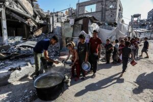 Palestinian children wait in queues as the US-based international volunteer aid organization, World Central Kitchen (WCK) distribute as many meals as they are able, given the severe shortage of food and fuel, due to Israel's blockade on the entrance of humanitarian aid, food and other products into Gaza on March 16, 2025 in Khan Younis, Gaza.