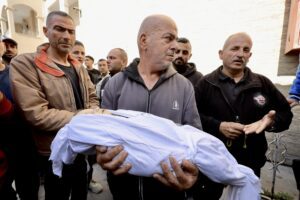 A Palestinian man carries a child killed during Israeli strikes on Gaza on 18 March, 2025