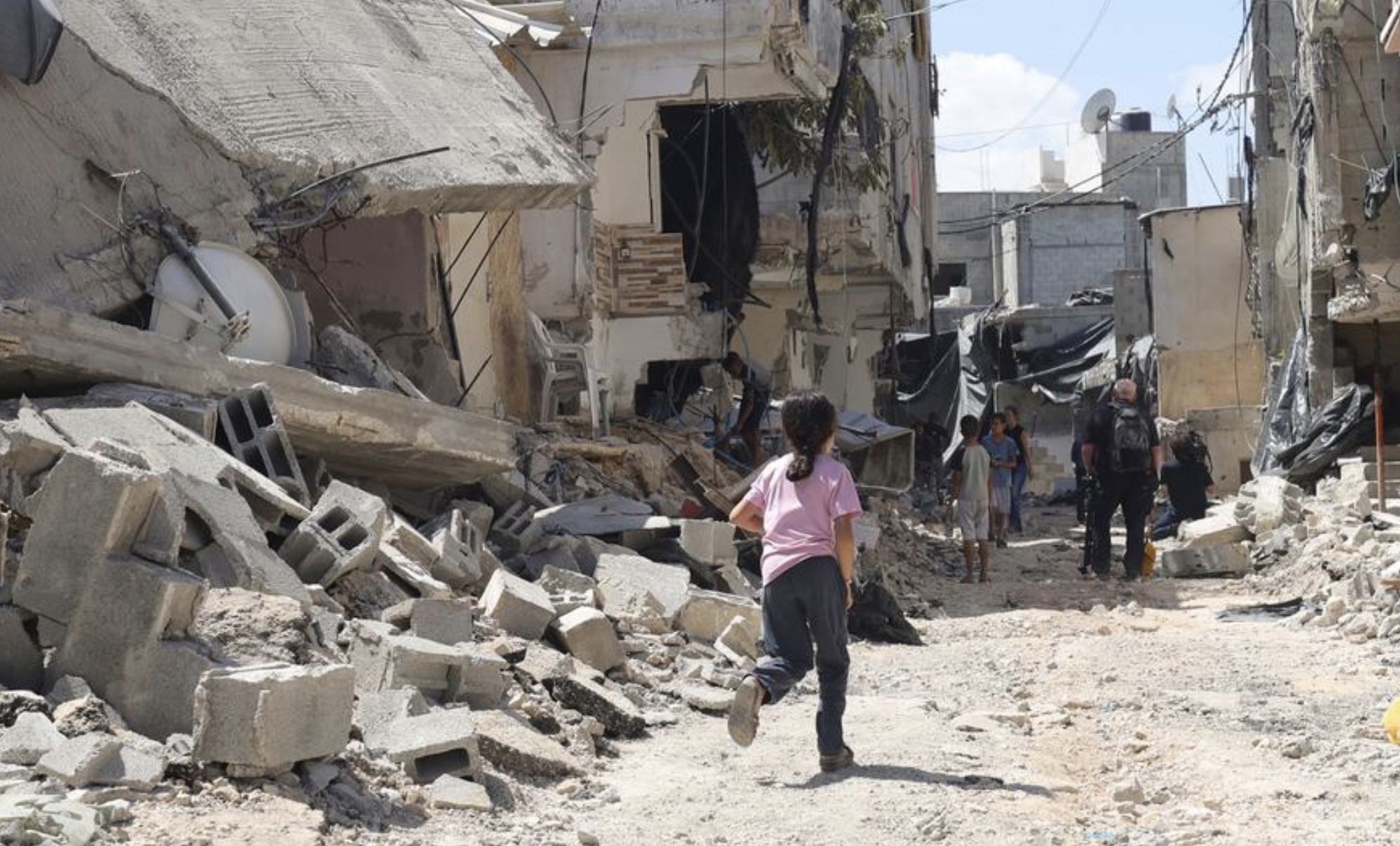 A young girl runs through the rubble of damaged buildings after an Israeli military raid at Nur Shams refugee camp, in the West Bank in August 2024.