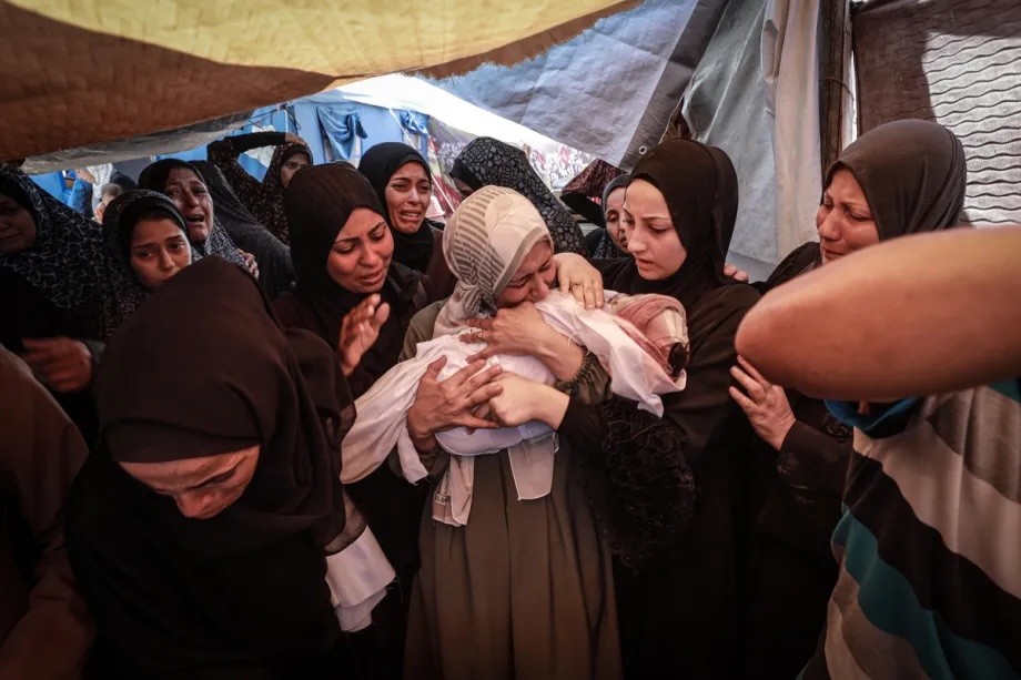 Women grieve over the body of a Palestinian child killed in an Israeli airstrike targeting the house of the Azzam family, in Gaza City, Gaza, on July 15, 2025.