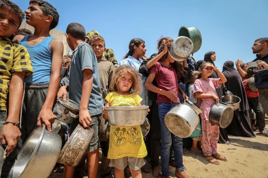 Palestinians, including children, gather as a charity distributes food in Gaza City, where residents face difficulties accessing basic supplies amid the ongoing Israeli blockade and attacks, on August 16, 2025.
