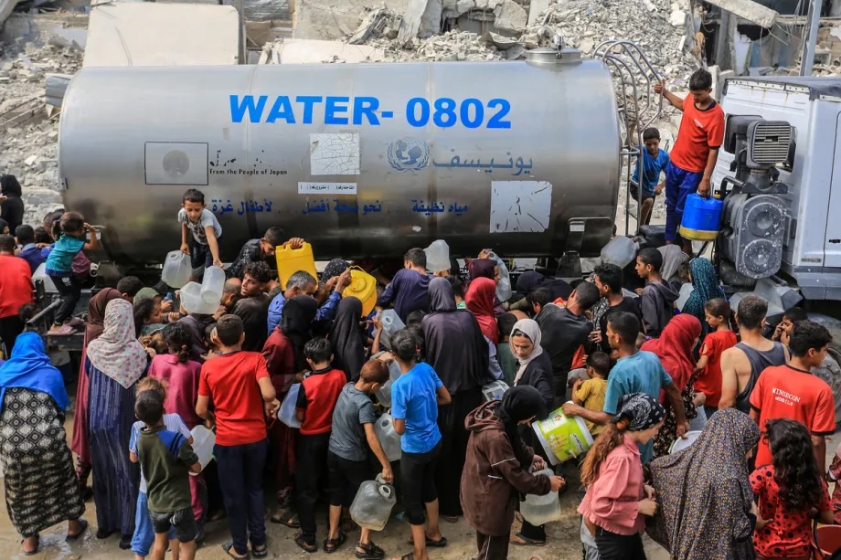Palestinians crowd around to fill their jerry cans from a UNICEF water tanker that just arrived, on August 18, 2025 in Khan Younis, Gaza.