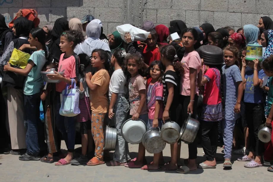 Palestinians, including children, who are struggling to access food due to Israel’s blockade and ongoing attacks on the Gaza Strip, wait in line to receive hot meals distributed by a charity organization at the Nuseirat refugee camp in Deir al-Balah, Gaza on August 18, 2025.
