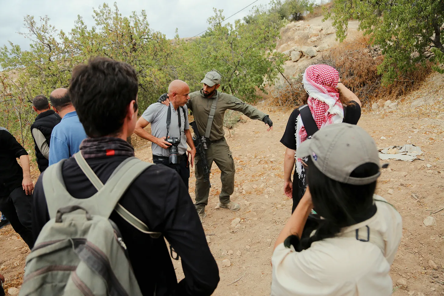 An armed Israeli settler violently restrains a photojournalist near the Palestinian village of Idhna, west of Hebron, on Oct. 12, 2025.