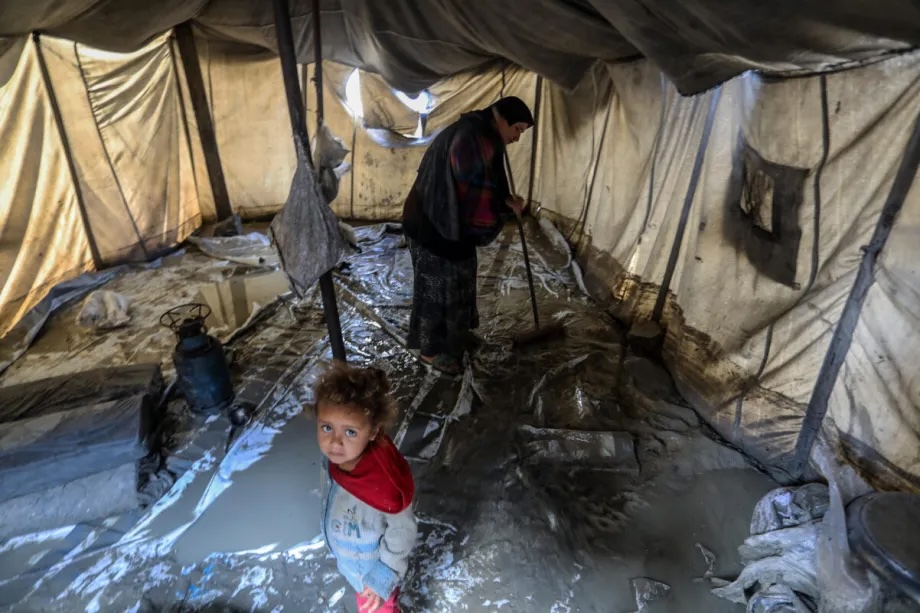 Displaced Palestinians try to protect their belongings from damage after heavy rain in the Austrian Quarter of Khan Younis, Gaza on November 16, 2025.