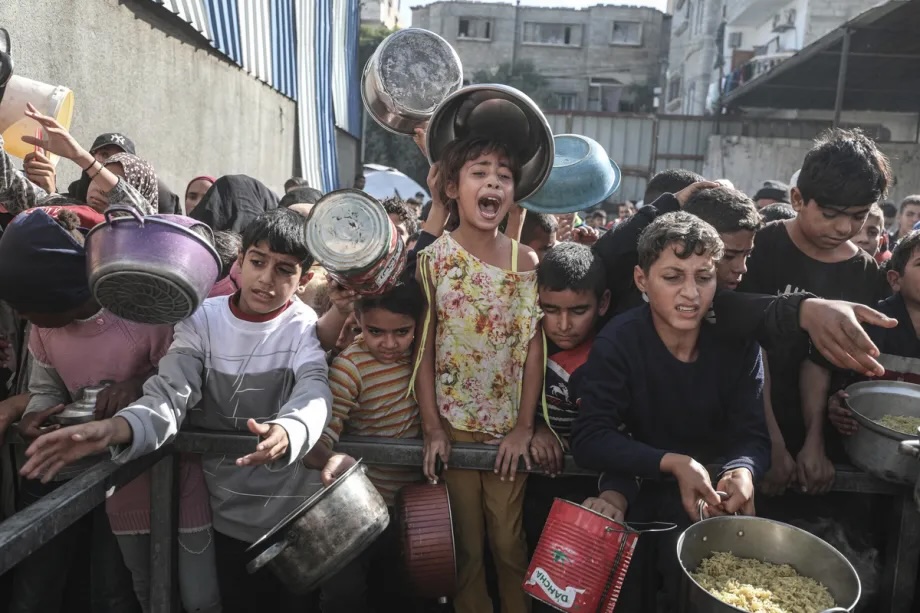 Displaced Palestinians wait to receive hot meal distributed by a charity organization in Nuseirat Camp, Gaza on November 22, 2025.