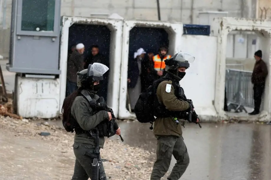 Israeli forces take security measures as Palestinians, living in West Bank, gather at the Qalendiya military checkpoint separating Ramallah and Jerusalem on March 21, 2025.