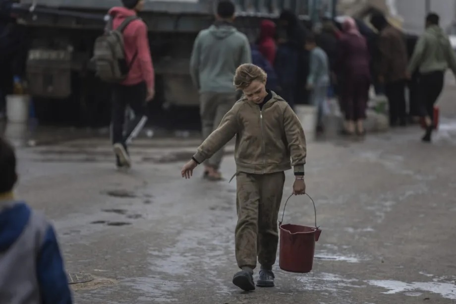 Palestinians carry water in jerrycans after collecting it from tanker trucks amid a severe water crisis caused by heavy damage to infrastructure following Israeli attacks in Gaza City in the northern Gaza Strip on December 29, 2025.