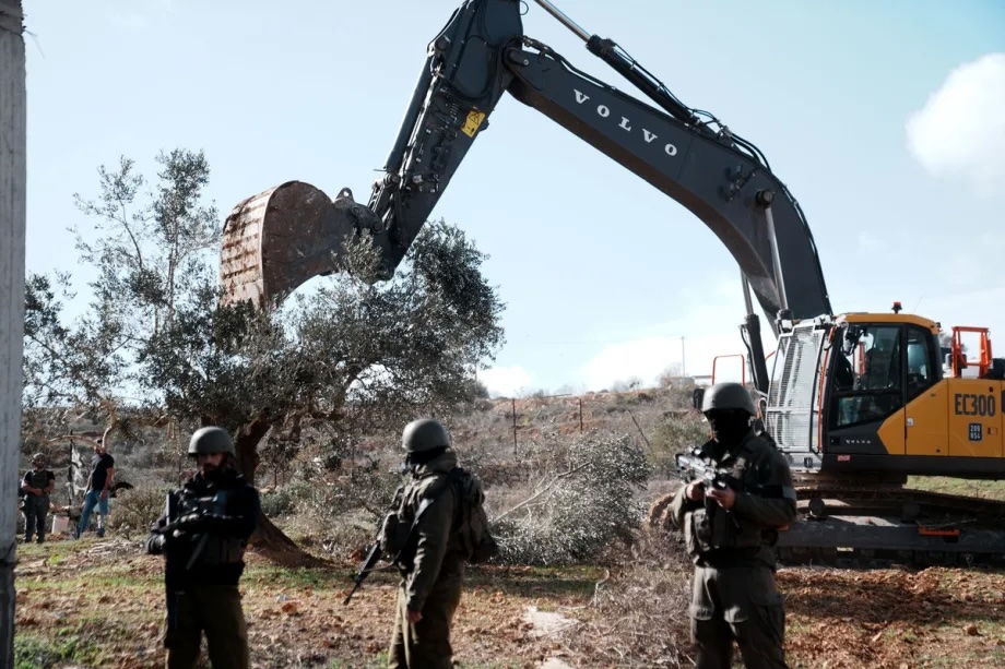 Israeli soldiers stand by as Israeli construction vehicles destroy agricultural lands and uproot centuries-old olive trees in the village of Karyut, south of the city of Nablus, West Bank on December 08, 2025.