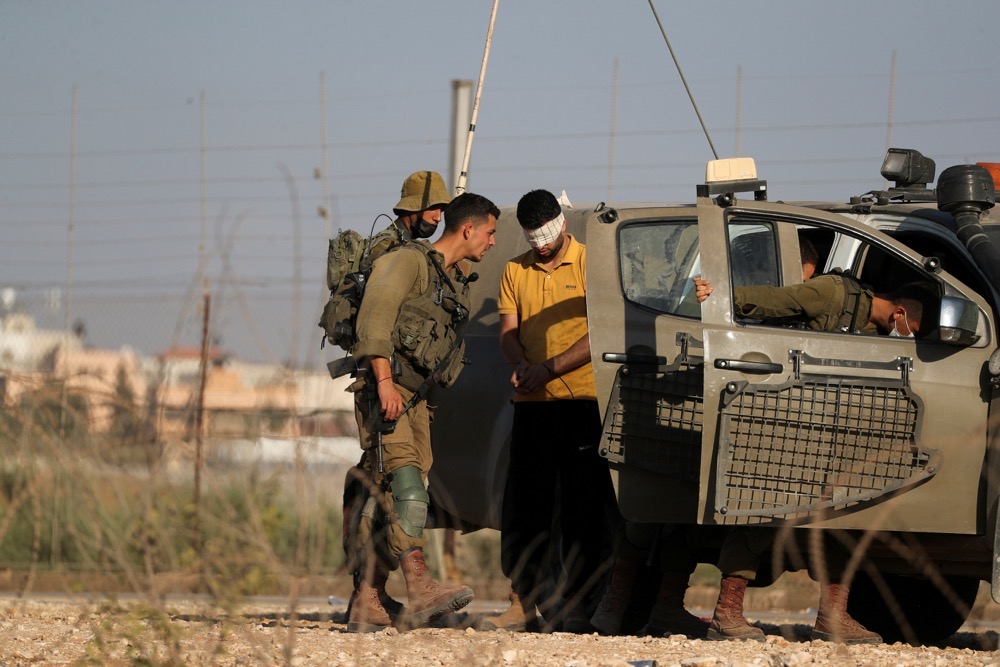 Israeli soldiers detain a Palestinian man by the village of Muqeibila near the entrance to the West Bank. (Reuters/File)
