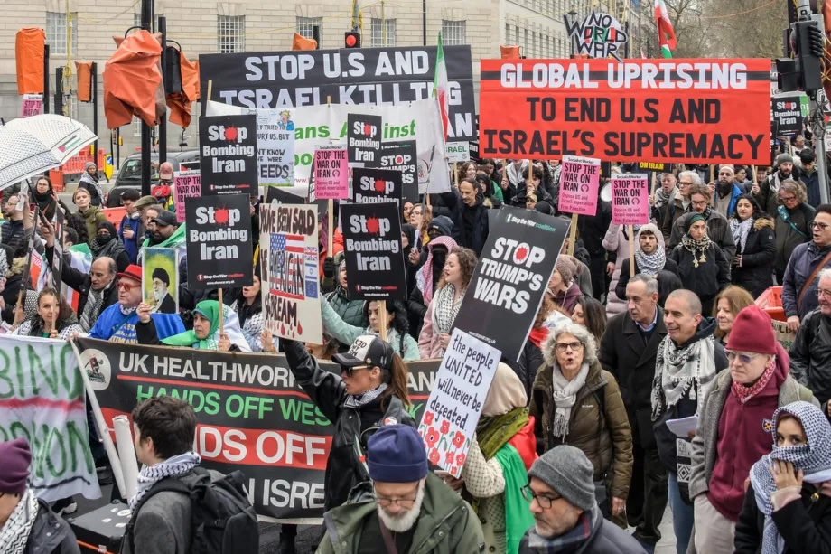 Protesters wave flags and banners reading “Stop Bombing Iran” and “Stop Bombing the Middle East” as they gather at Victoria Tower Gardens before marching toward the United States Embassy to protest the war in the Middle East in London, United Kingdom, on March 07, 2026.