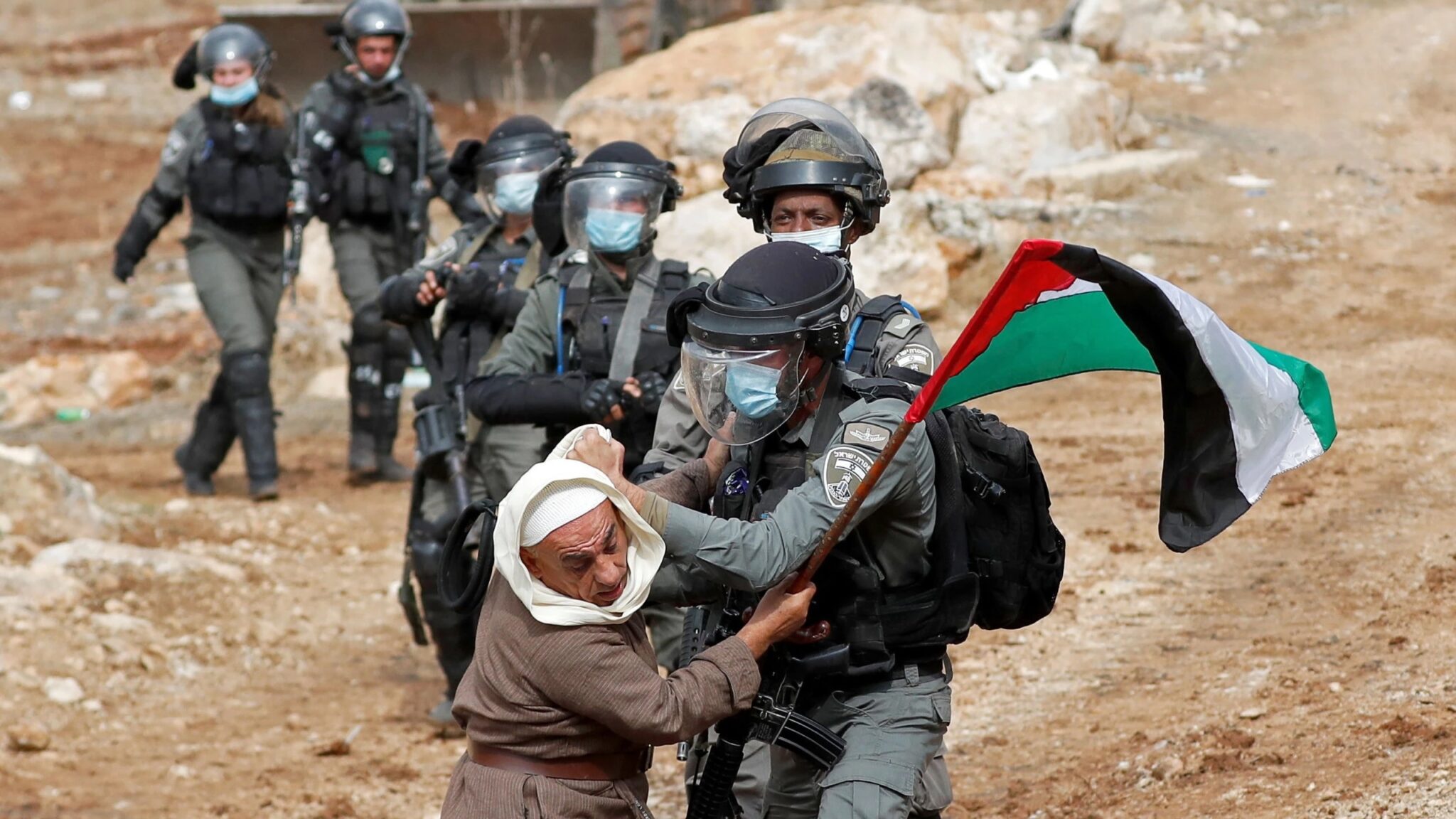 Israeli soldiers assault an elderly Palestinian man carrying a Palestinian flag, West Bank.
