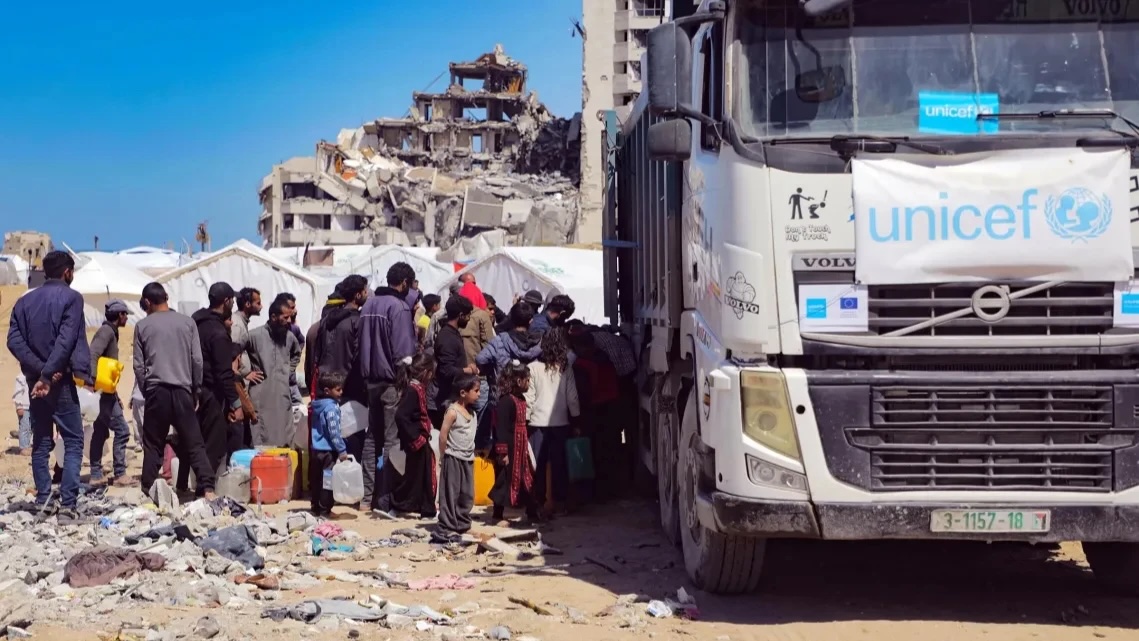 Displaced Palestinians near Beach Camp north-west of the Gaza City gather around a UNICEF truck carrying tanked water.