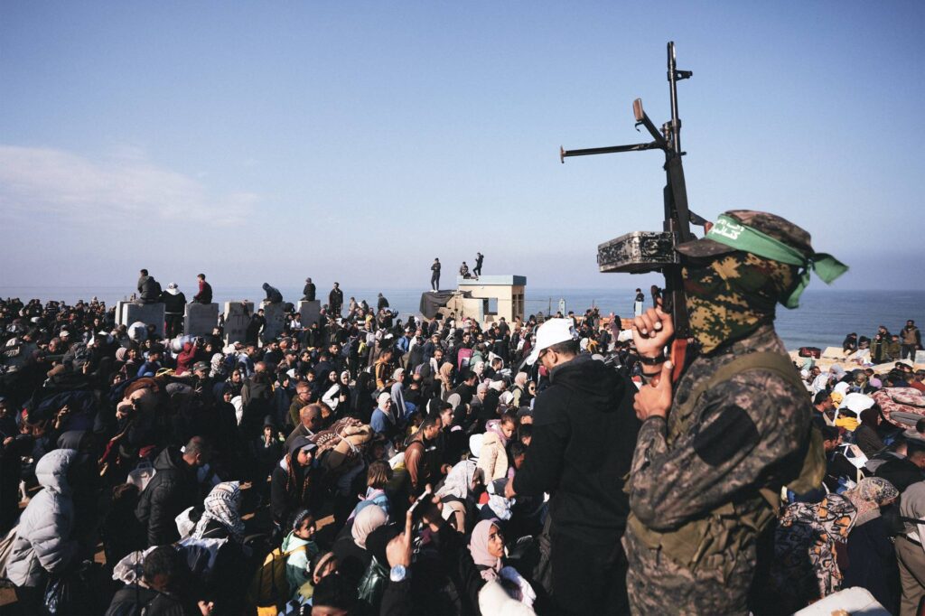 A Hamas fighter stands near displaced Palestinians in northern Gaza.