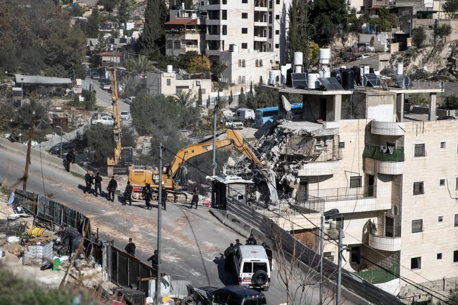 Israeli forces demolish a residential building containing 13 apartments and housing nearly 100 Palestinians in the Wadi Qadum neighborhood of East Jerusalem, claiming it lacked a permit, on December 22, 2025. 