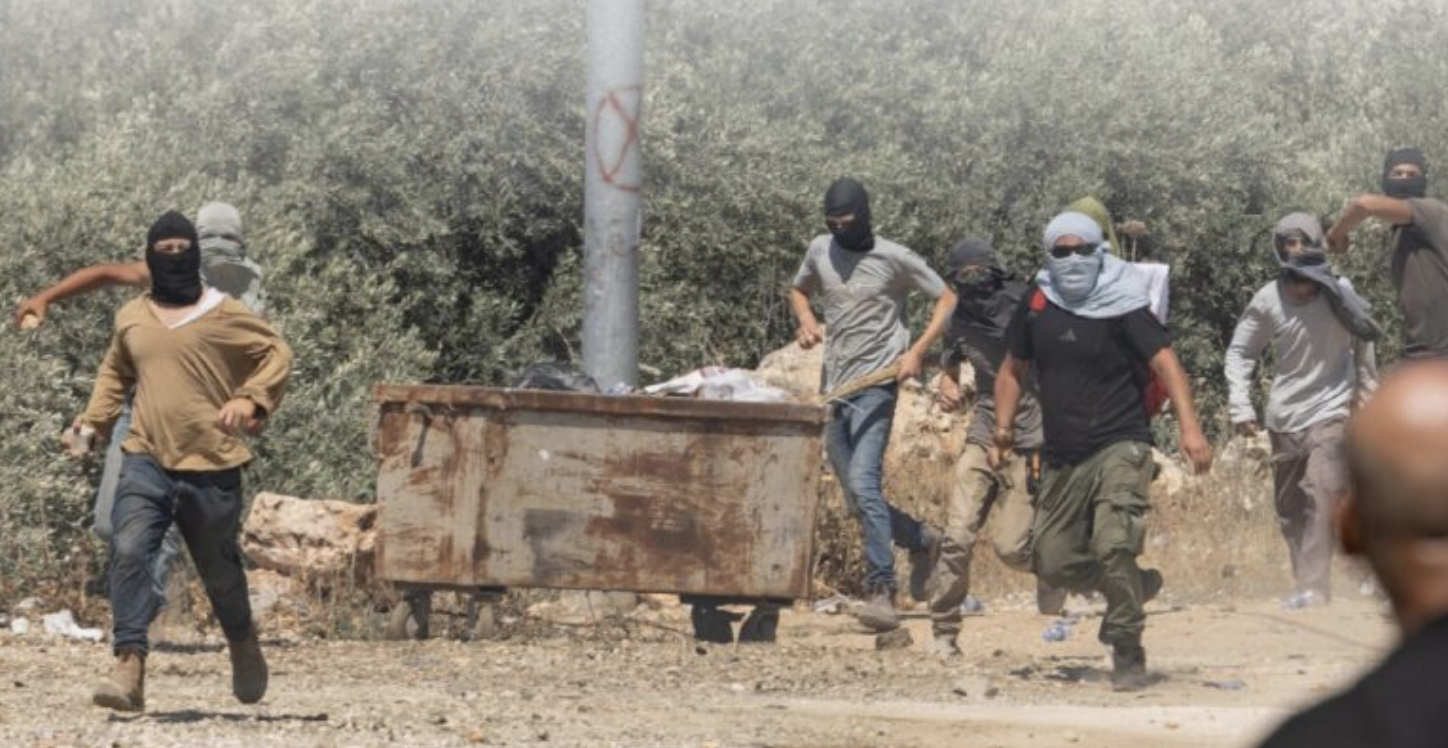 Group of masked men approaching the camera threateningly, with one on the far right in the act of throwing something.