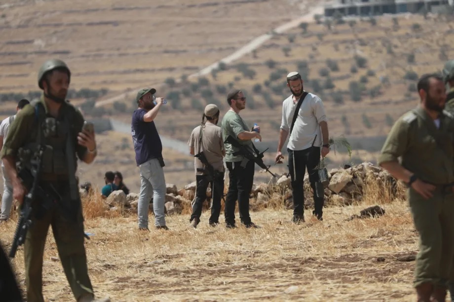 Armed Israeli settlers and soldiers gather in Beit Sahour, Hebron Governorate, West Bank, on August 14, 2026, where Palestinians and foreign activists gather to protest against Israel's policies of aggression and land seizure