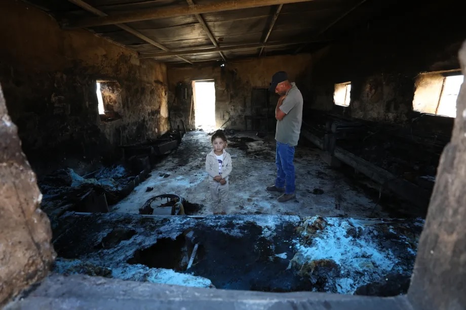A Palestinian man and a girl stand inside a home burned by Israeli settlers in the Khirbet al-Tuba community in the Masafer Yatta area, south of Hebron, West Bank, Palestine on August 6, 2026. 

